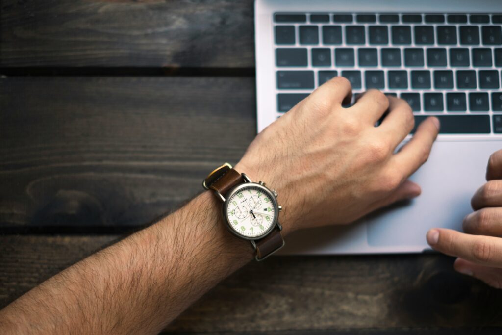 picture of a watch on mans arm with laptop