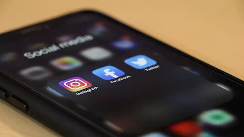 Mobile phone showing social media apps on screen like Instagram, Facebook and Twitter (now known as X)
