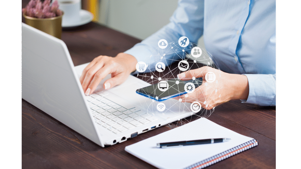 Image of a business woman sitting at a desk, with laptop, phone and notepad. Icons of different ways to communicate overlay the image in white. Indicating the multiple ways to communicate with a VA.