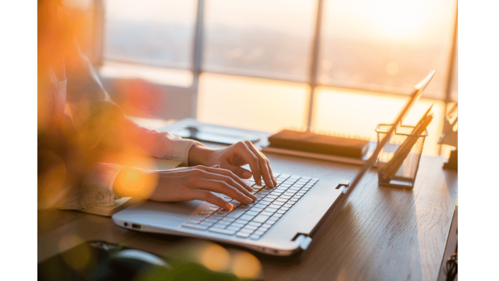 A laptop with finger poised at a desk, indicating someone busy at work, looking into hiring a VA.